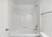 Thumbnail 12 of 29 - A white bathroom with a tub, toilet, and sink.