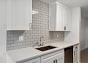 Thumbnail 13 of 29 - A kitchen with white cabinets and a grey tile backsplash.