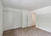 Thumbnail 16 of 29 - A room with white walls and carpeted floor with three doors.