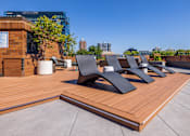 Thumbnail 30 of 33 - a row of black lounge chairs on a wooden deck on a roof