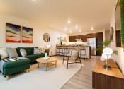 Thumbnail 9 of 18 - a living room with a couch and a table in front of a kitchen