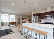 Thumbnail 16 of 18 - an open kitchen and dining room with a large white counter top and chairs
