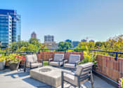 Thumbnail 32 of 33 - a rooftop patio with chairs and a fire pit and a city in the background