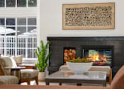 Thumbnail 22 of 38 - A living room with a fireplace and a painting above it.