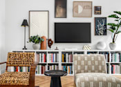 Thumbnail 24 of 38 - A living room with a chair, a table, and a bookshelf.