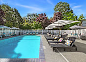 Thumbnail 28 of 38 - A large outdoor swimming pool surrounded by lounge chairs and umbrellas.