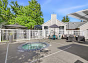 Thumbnail 30 of 38 - A hot tub is in the middle of a patio with a white fence and a house in the background.
