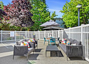 Thumbnail 32 of 38 - A patio with a white fence and a black umbrella.