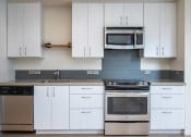 Thumbnail 12 of 33 - a kitchen with white cabinets and stainless steel appliances