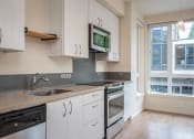 Thumbnail 22 of 33 - a kitchen with white cabinets and a sink and a microwave