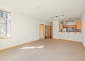 Thumbnail 29 of 42 - an empty living room with a kitchen and a window