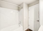 Thumbnail 24 of 40 - a bathroom with a white tub and shower and a white door