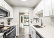Thumbnail 11 of 40 - an empty kitchen with white cabinets and a stove and a sink