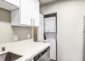 Thumbnail 12 of 40 - a kitchen with white cabinets and a washer and dryer in it
