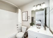 Thumbnail 14 of 15 - a bathroom with a white sink and toilet next to a bathtub with a shower curtain and
