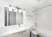 Thumbnail 38 of 49 - A white bathroom with a toilet, sink, and bathtub.