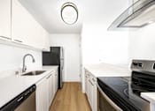 Thumbnail 23 of 49 - A modern kitchen with white cabinets and black appliances.