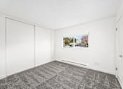 Thumbnail 43 of 49 - A room with a grey carpet and a white wall with a picture of a house on it.