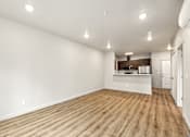 Thumbnail 14 of 32 - A spacious room with wooden flooring and white walls.