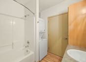 Thumbnail 35 of 42 - a bathroom with a sink and a shower and a washer and dryer