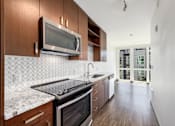Thumbnail 11 of 38 - a kitchen with marble counter tops and wooden cabinets and a microwave over the stove