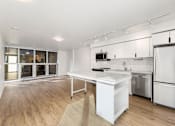 Thumbnail 7 of 26 - A modern kitchen with a white island and stainless steel appliances.