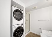 Thumbnail 11 of 26 - A white washing machine and dryer stacked on top of each other in a small room.