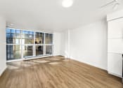 Thumbnail 9 of 26 - A room with wooden flooring and a large window with a view of a cityscape.