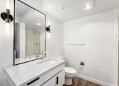 Thumbnail 10 of 26 - A white bathroom with a sink, toilet, and mirror.