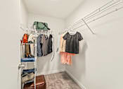 Thumbnail 30 of 34 - a walk in closet with clothes hanging on a rack and a door to a wardrobe