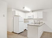 Thumbnail 7 of 16 - A white kitchen with a fridge, microwave, dishwasher, and sink.