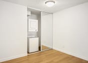 Thumbnail 29 of 49 - A white refrigerator is in a room with a white wall and wooden floor.