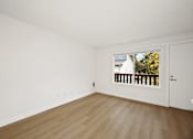 Thumbnail 37 of 49 - A room with a white door and a window showing a balcony with a white house and trees in the background.