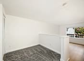 Thumbnail 47 of 49 - A room with a carpeted floor and a window with a view of a balcony.