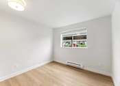 Thumbnail 6 of 26 - A room with a window and a wooden floor.