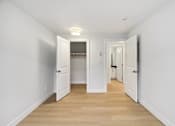 Thumbnail 5 of 26 - A long hallway with white walls and wood floors.