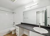 Thumbnail 7 of 26 - A white bathroom with a black counter top and a white toilet.
