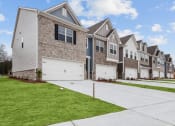 Thumbnail 31 of 31 - a row of houses with white garage doors and a green lawn