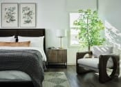 Thumbnail 35 of 48 - a bedroom with a bed and a chair and a plant