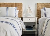 Thumbnail 41 of 48 - a bedroom with two twin beds and a nightstand with a sailboat on it