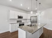 Thumbnail 7 of 31 - a kitchen with white cabinets and a granite counter top