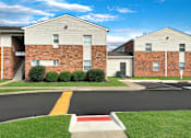 Thumbnail 24 of 25 - A street view of a residential area with apartment buildings and a parking lot.