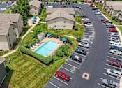 Thumbnail 1 of 31 - A parking lot with cars and a swimming pool in the middle of a residential area.