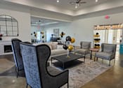 Thumbnail 11 of 15 - A living room with a grey sofa, a black coffee table, and a fireplace.