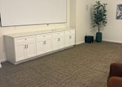 Thumbnail 15 of 15 - A room with a brown chair and a white cabinet with drawers.
