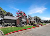 Thumbnail 8 of 26 - A red flowering tree is in front of a building.