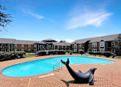 Thumbnail 26 of 26 - A pool with a seal statue in front of apartment buildings.