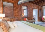 Thumbnail 8 of 34 - a bedroom with a bed and a brick wall