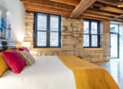 Thumbnail 1 of 34 - a bedroom with a bed and a stone wall