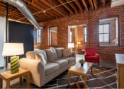 Thumbnail 14 of 34 - a living room with a couch in front of a brick wall